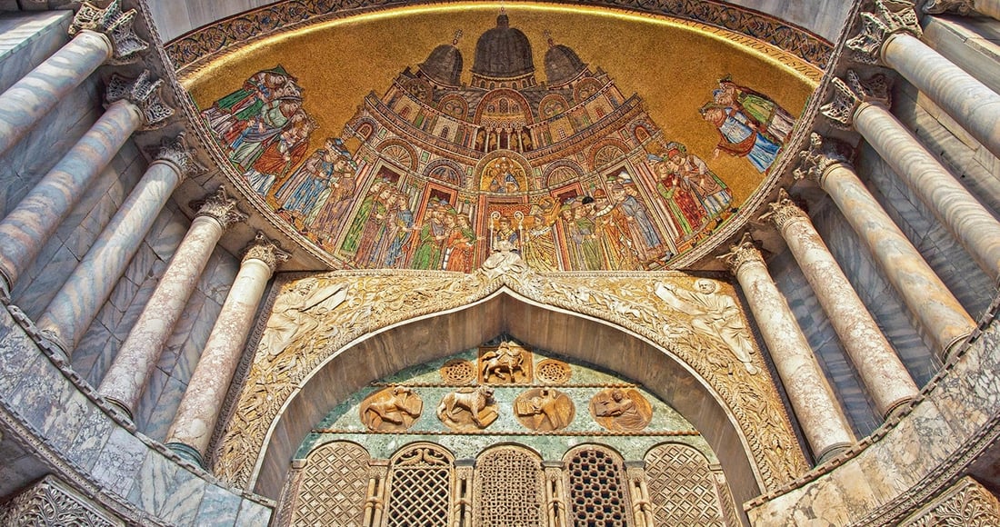 The golden mosaics and ornate carved stone above the main doorway of St Mark's Basilica in Venice