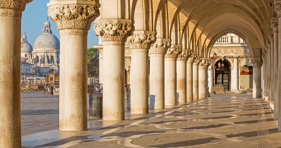 The marble colonnade of the Doge's Palace on St Mark's Square, looking out towards the domed church of Santa Maria della Salute