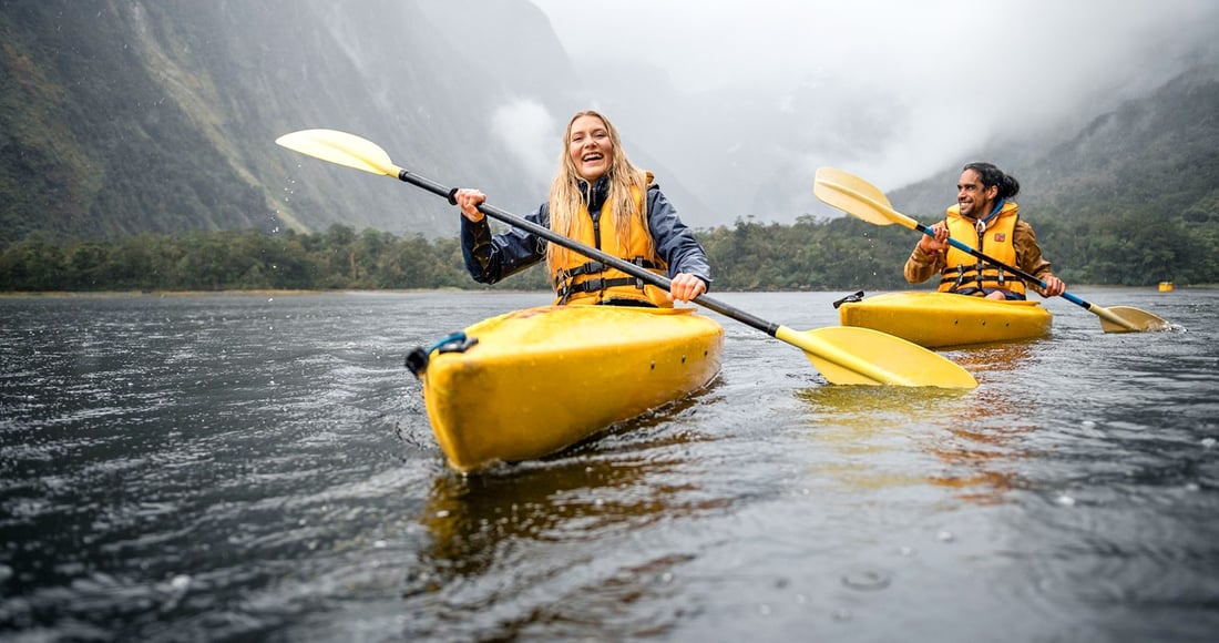 Overnight cruise vessel moored in Milford Sound beneath steep forested cliffs at dusk