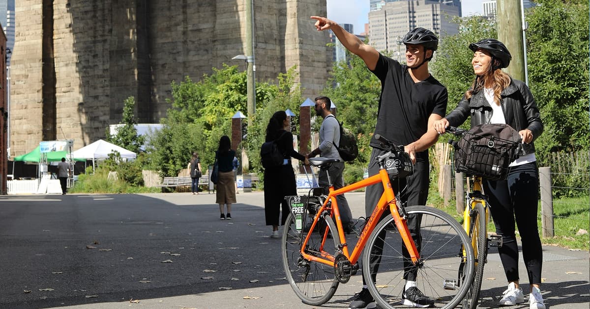 Walkers and cyclists crossing the Brooklyn Bridge with the Manhattan skyline behind