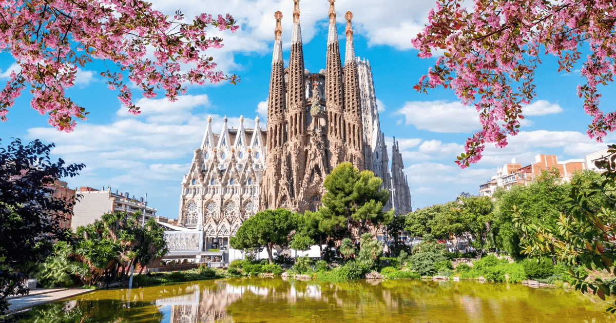The completed Sagrada Família in Barcelona seen across the lake, framed by blossom