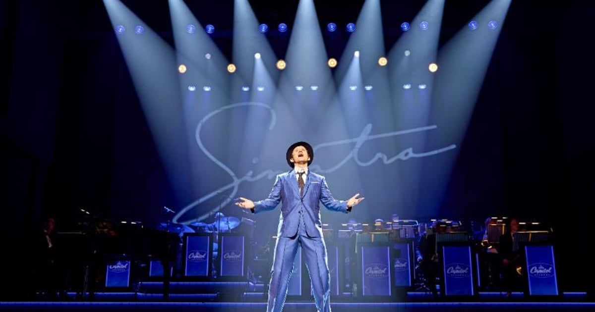 Joel Harper-Jackson as Frank Sinatra under blue spotlights in Sinatra: The Musical at the Aldwych Theatre