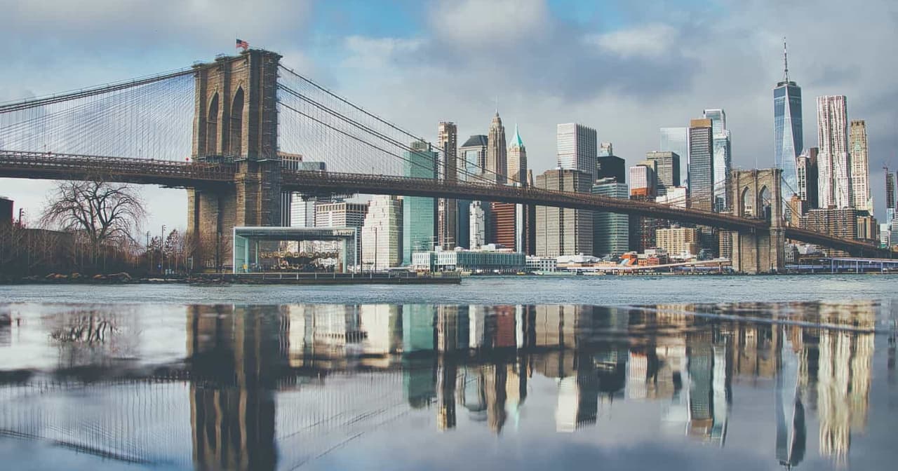 Brooklyn Bridge and Lower Manhattan skyline reflected in calm water, New York City