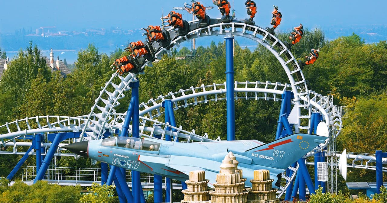 Looping roller coaster with riders at Gardaland theme park near Verona under a blue sky
