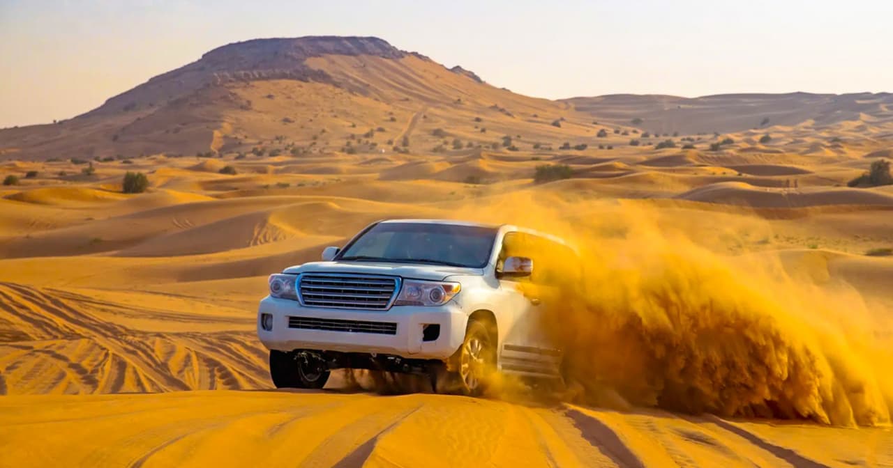 White 4x4 speeding through golden desert dunes on an Abu Dhabi safari