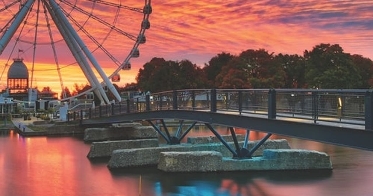 La Grande Roue ferris wheel and footbridge reflected in the water at sunset in Montreal