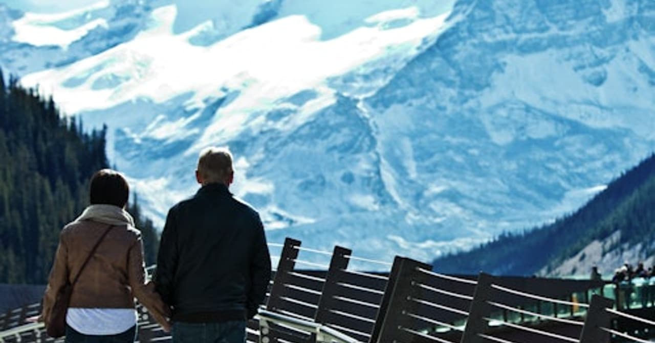 A couple walk along the scenic skywalk overlooking the mountains.