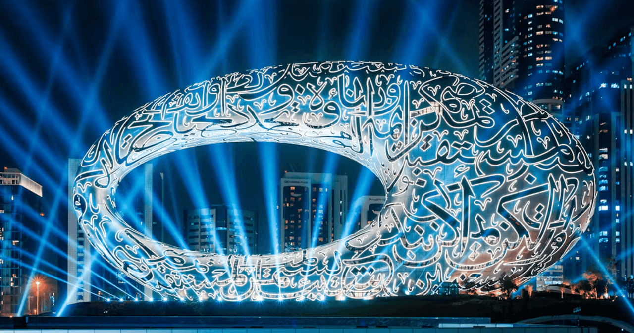 Museum of the Future in Dubai lit by blue light beams at night with Arabic calligraphy facade