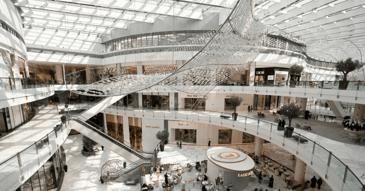 Sunlit luxury mall atrium in Dubai with a glass roof, multiple levels and designer storefronts