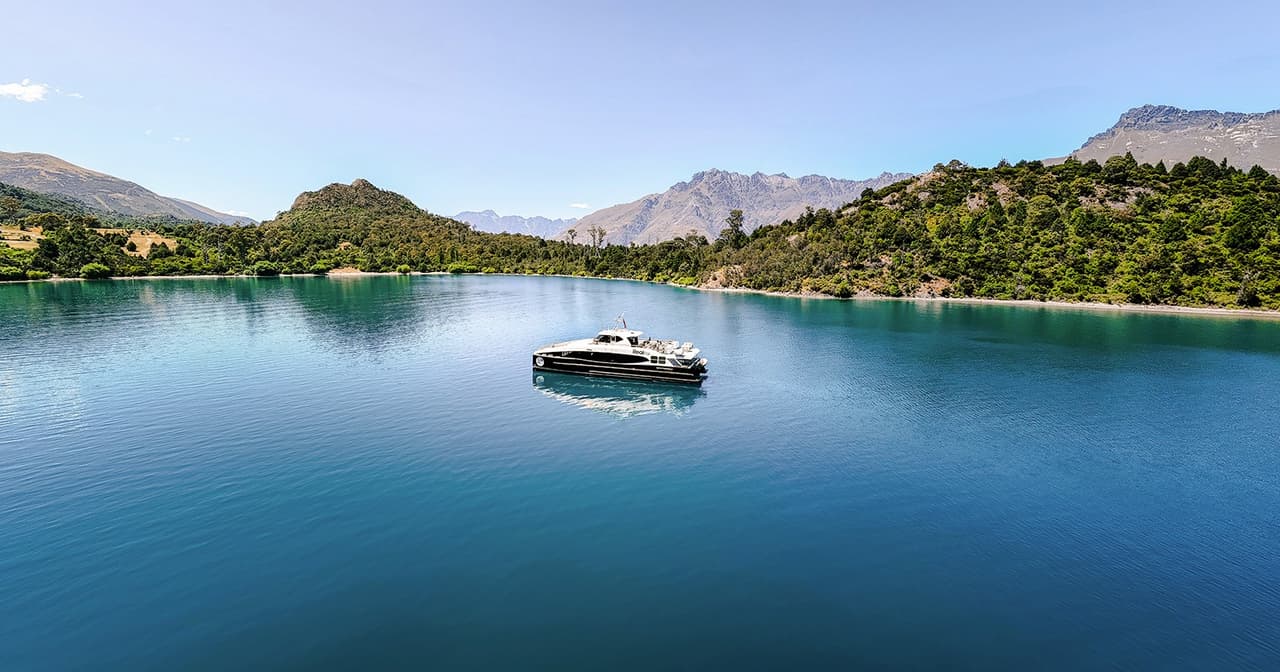 Sleek cruise boat on the blue waters of Lake Wakatipu framed by mountains near Queenstown, New Zealand