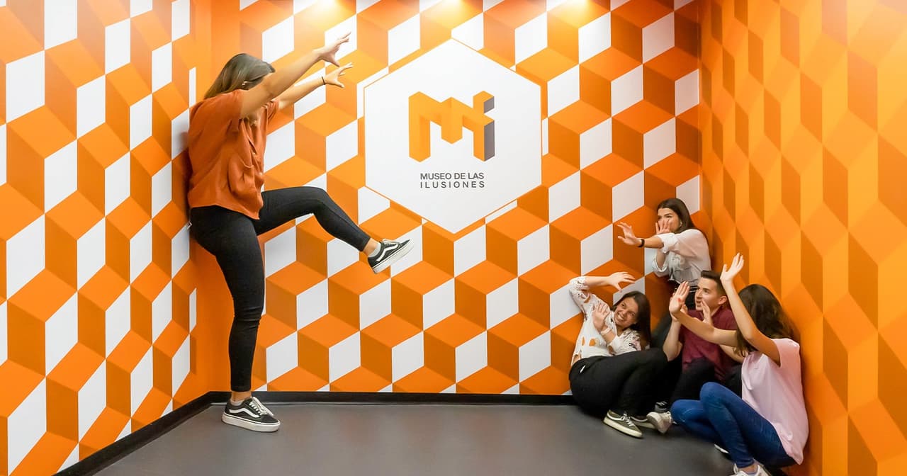 People posing in an orange geometric optical illusion room at Seville's Museum of Illusions