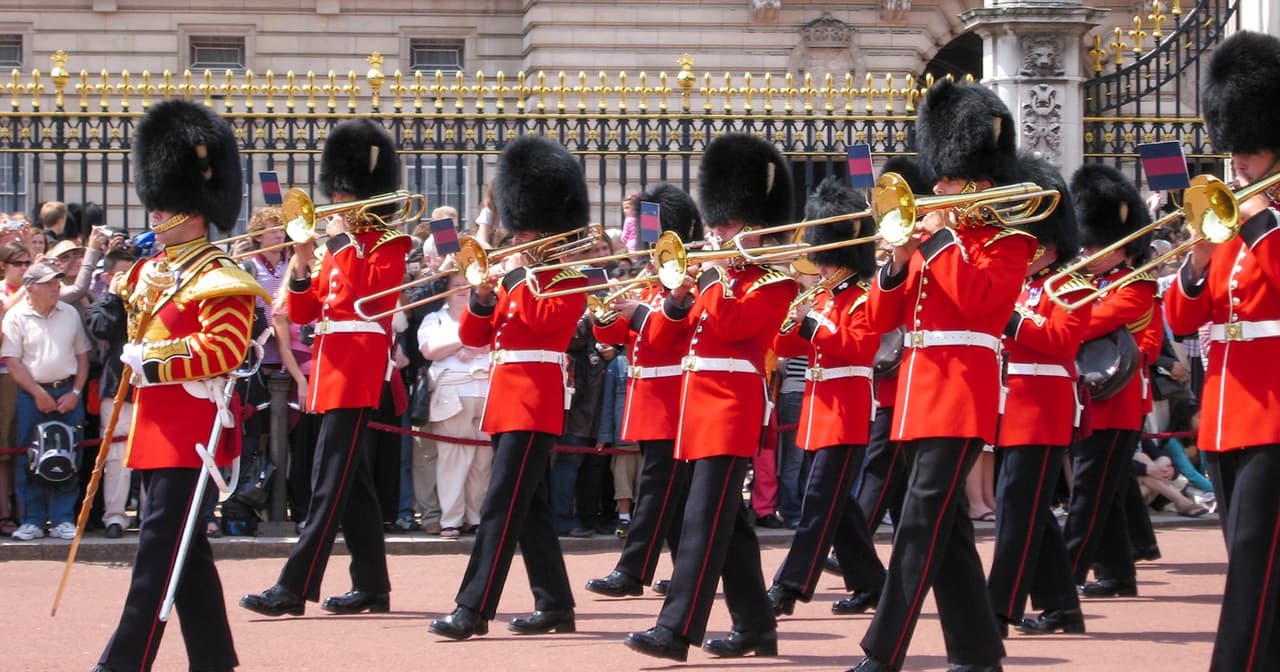 Guards in red uniforms and bearskin hats perform at Changing of the Guard, London.