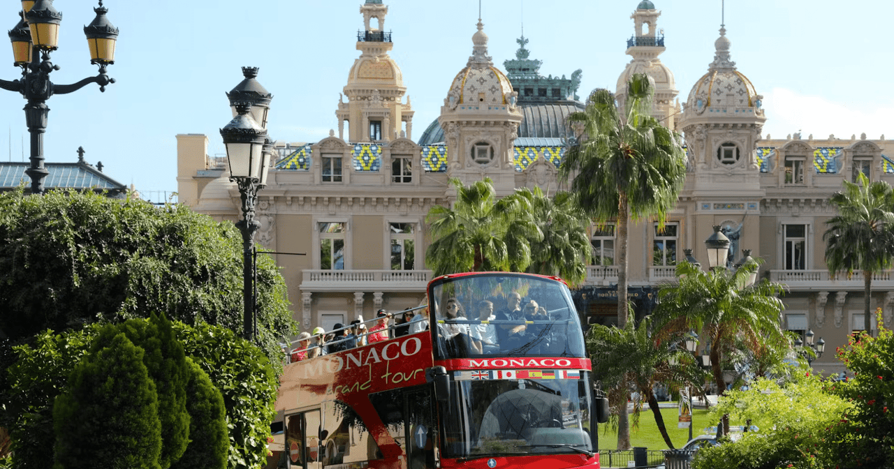 Red Monaco open-top sightseeing bus passing the grand Monte Carlo Casino facade