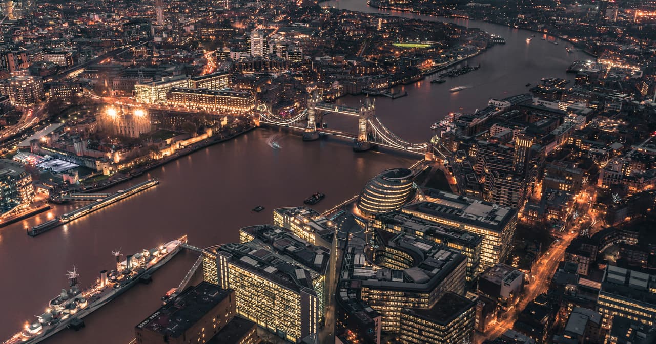 Aerial night view of London with the lit Thames, Tower Bridge and glowing city skyline