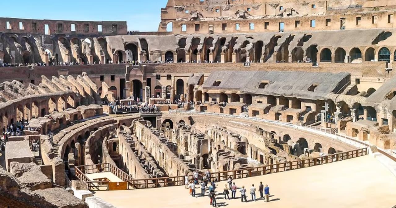 Interior of the Roman Colosseum in Rome with tiered ruins and visitors on the arena floor