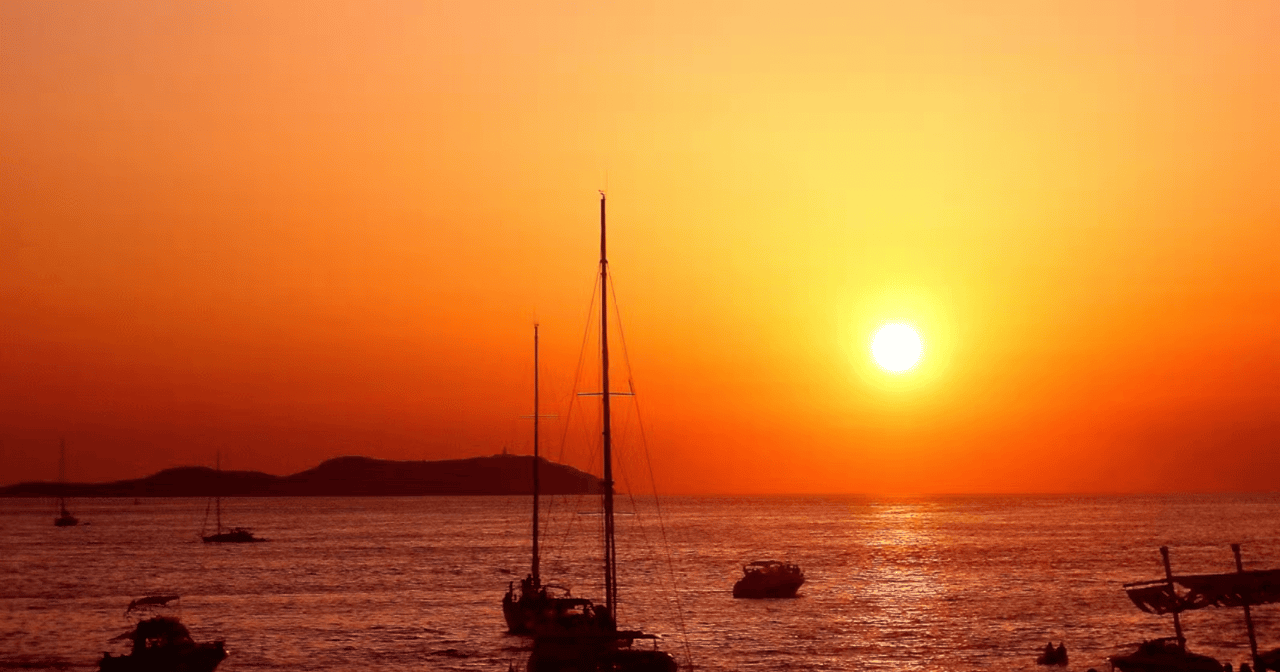 Sunset over the sea in Ibiza with boats on the water
