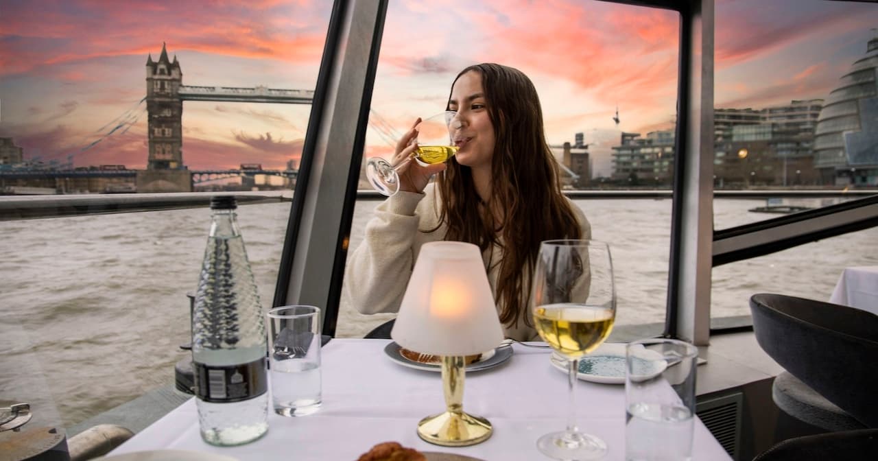 Couple dining on a Thames sunset cruise with Tower Bridge behind