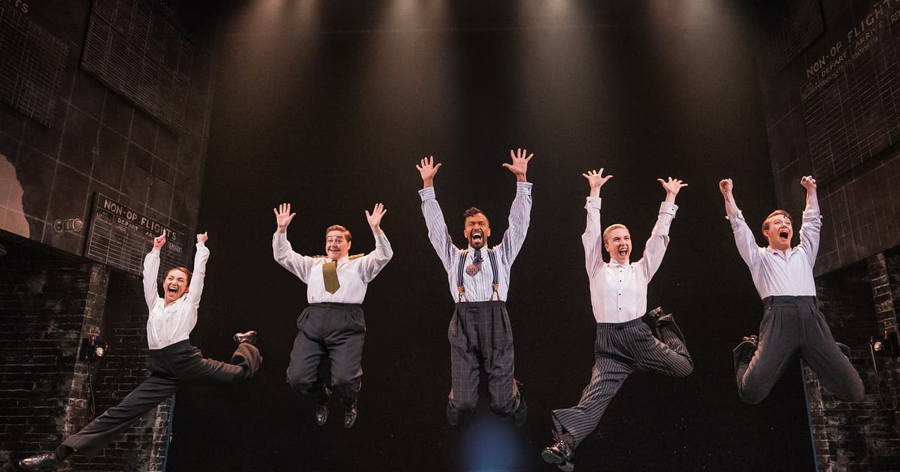 The cast of Operation Mincemeat leaping into the air on stage at the Golden Theatre