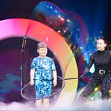 A child standing inside a giant bubble on stage at The Gazillion Bubble Show in New York