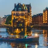 The Speicherstadt's Wasserschloss lit up at dusk above a canal in Hamburg
