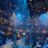 A full house at the Old Vic theatre in London during a performance, with lanterns hanging above the stage