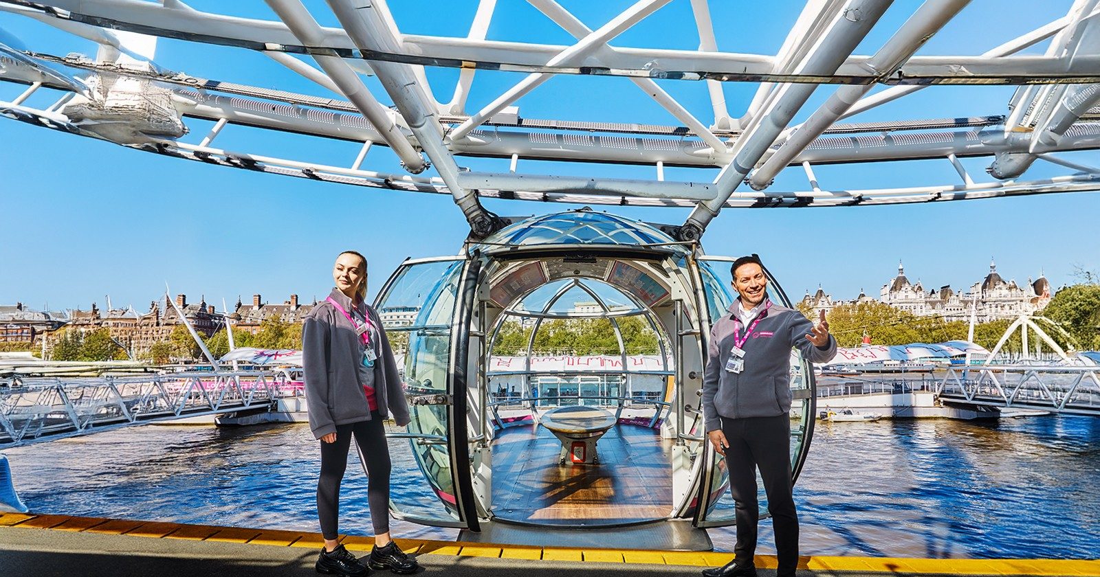 London Eye capsule entrance with staff welcoming visitors, view of Thames River.