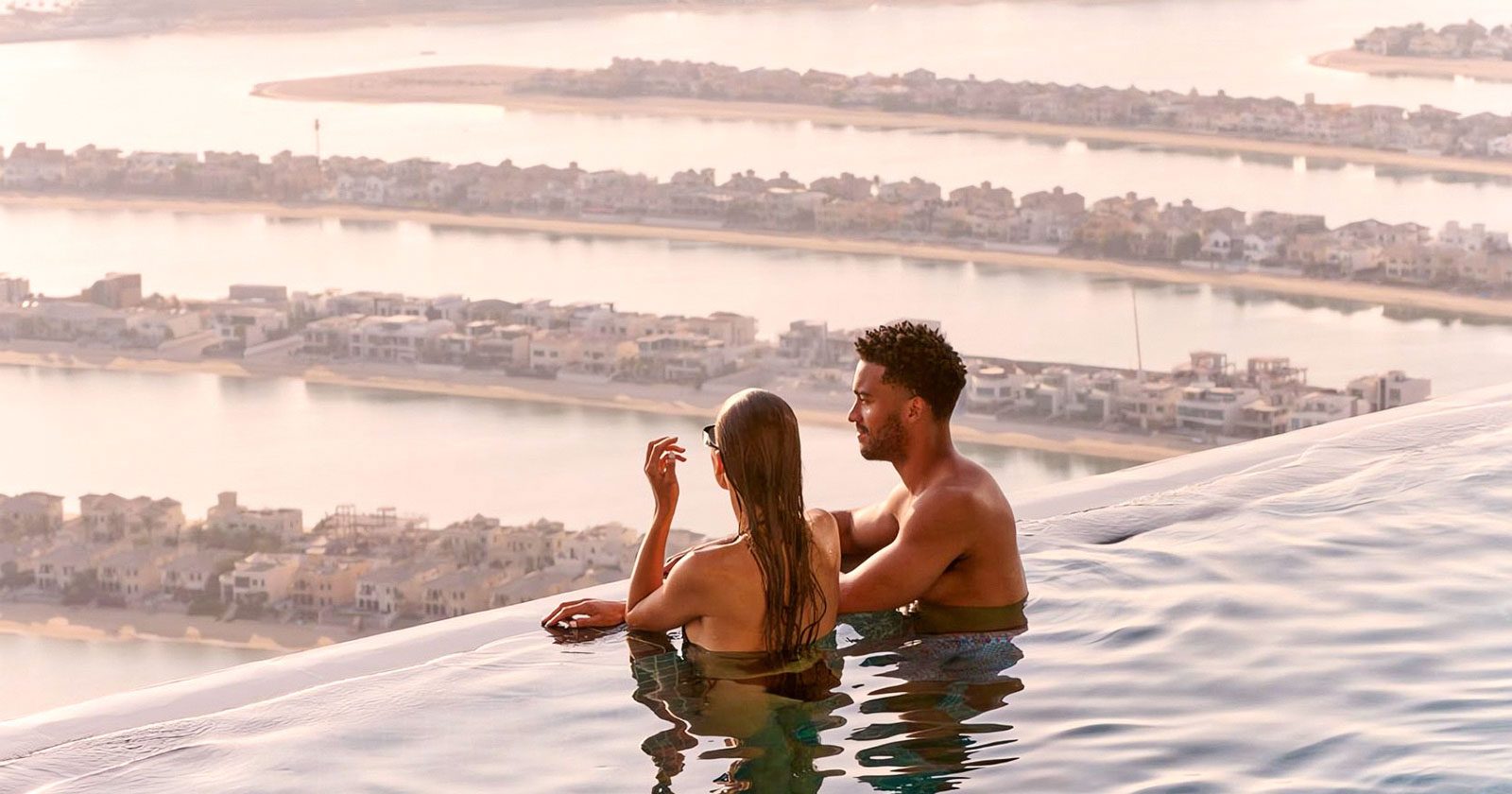 A couple experience sunrise at the edge of the AURA infinity pool looking out over the Palm.