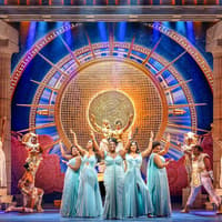 Stage performance of Disney's Hercules with actors in Greek costumes and ornate backdrop