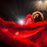 Performer in vibrant red costume on stage during Kinky Boots production