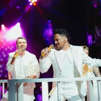 Performers singing at Mamma Mia! The Party with vibrant stage lights