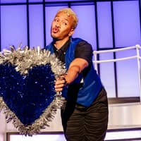 Performer holding a glittery heart prop on stage during Titanique Westend show