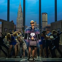 Stage scene from The Devil Wears Prada West End show with city skyline backdrop