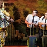 Performers in "The Book of Mormon" musical scene with vibrant costumes and props