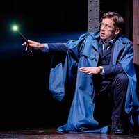 Actor holding a glowing wand in "Harry Potter and the Cursed Child" stage scene