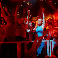 Audience enjoying Mamma Mia! The Party performance with vibrant lights and festive atmosphere