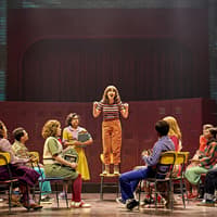 Group of students in a school setting, one standing on a chair, from Stranger Things: The First Shadow