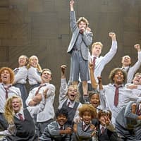 Cast of Matilda The Musical performing on stage with raised fists
