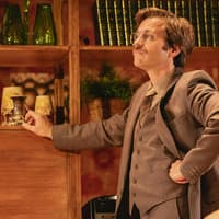 Stage scene from Abigail's Party, Westend, featuring a man in a suit with a vintage decor backdrop