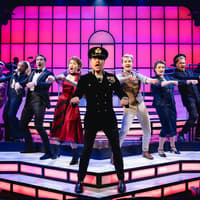 Cast performing a musical number in Titanique Westend with vibrant stage lighting