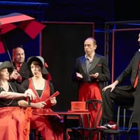 Performers in red and black costumes on stage during Showstopper! The Improvised Musical
