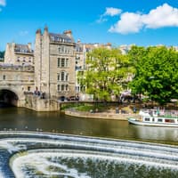 Historic Bath city street with tour group near Pulteney Bridge, live music performance nearby — Bridgerton: 1.5 Hour Guided Tour of Filming Locations in Bath with Music