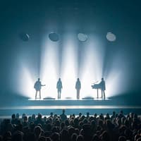 Silhouetted performers on stage with audience at ABBA Voyage show in London