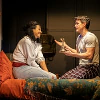 Stage scene from Paranormal Activity, Westend, with two actors on a bed discussing a bell