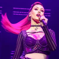Performer singing on stage during the musical "Six" with vibrant lighting