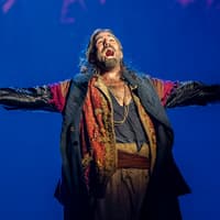 Performer in costume on stage during Oliver production