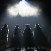 Four actors in costume stand on a dimly lit stage for Into The Woods production