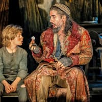 Actors in period costumes performing a scene from "Oliver" on stage