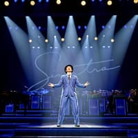 Performer on stage during Sinatra The Musical, Westend, with band and signature backdrop