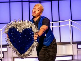 Performer holding a glittery heart prop on stage during Titanique Westend show