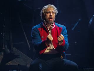 Performer in Les Misérables musical scene, wearing a red and blue costume